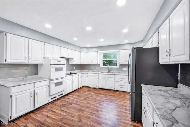 kitchen with light stone counters, sink, hardwood / wood-style floors, white cabinets, and white appliances