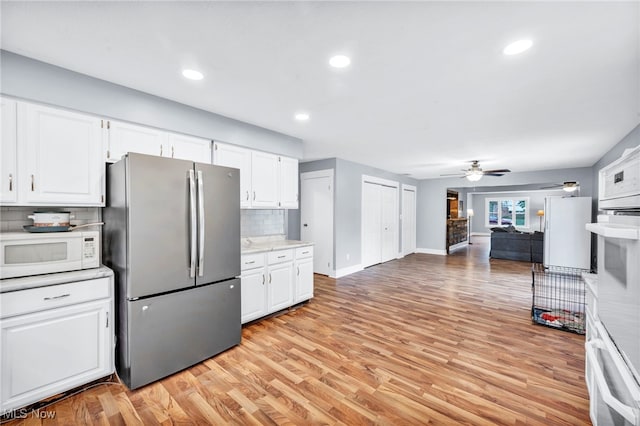 kitchen with light hardwood / wood-style flooring, backsplash, stainless steel refrigerator, and white cabinets