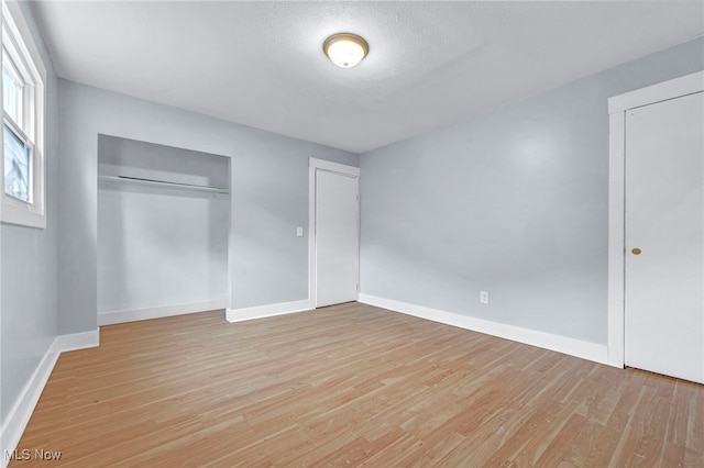 unfurnished bedroom with a textured ceiling, a closet, and light wood-type flooring