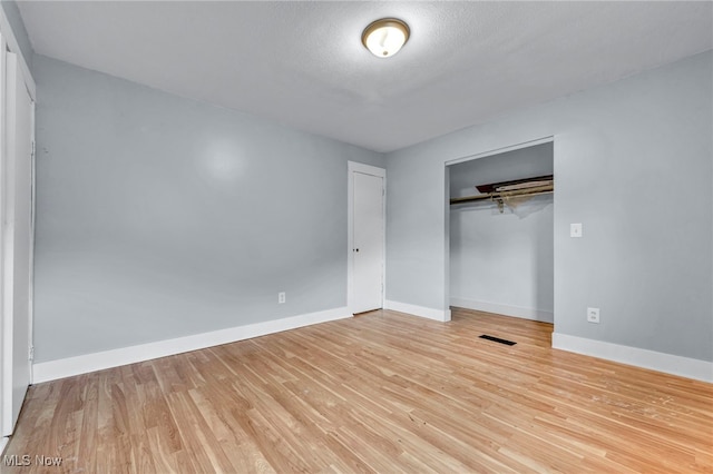 unfurnished bedroom featuring light wood-type flooring, a textured ceiling, and a closet