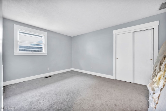 unfurnished bedroom featuring carpet floors, a textured ceiling, and a closet