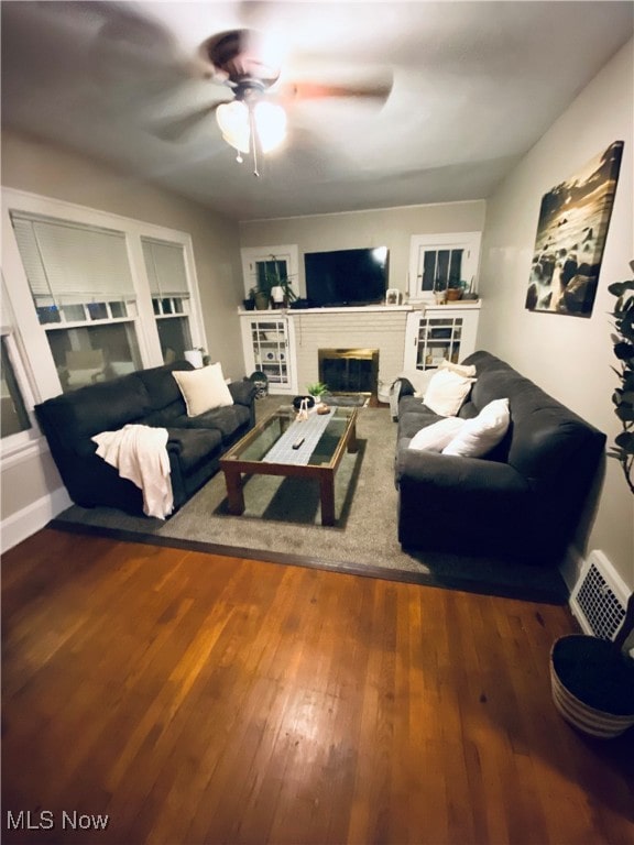 living room with ceiling fan, hardwood / wood-style flooring, and a fireplace