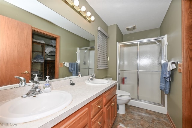 bathroom featuring vanity, toilet, and a shower with door