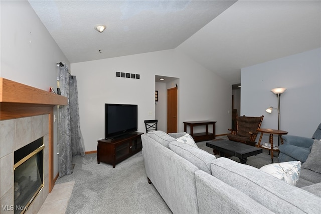 living room featuring light carpet, vaulted ceiling, and a tile fireplace