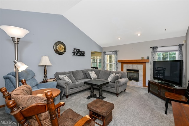 carpeted living room featuring a healthy amount of sunlight, vaulted ceiling, and a tiled fireplace