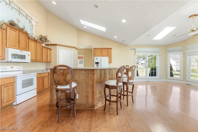 kitchen with light wood-type flooring, white appliances, ceiling fan, and a skylight