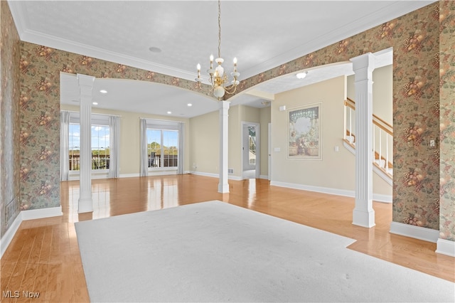 unfurnished room with light hardwood / wood-style flooring, crown molding, an inviting chandelier, and ornate columns