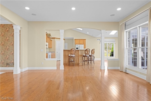 interior space with vaulted ceiling, light hardwood / wood-style floors, and ornate columns