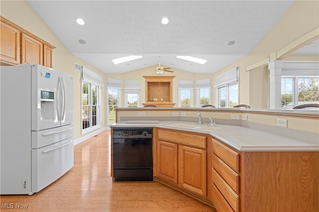 kitchen featuring vaulted ceiling with skylight, black dishwasher, white refrigerator with ice dispenser, and plenty of natural light