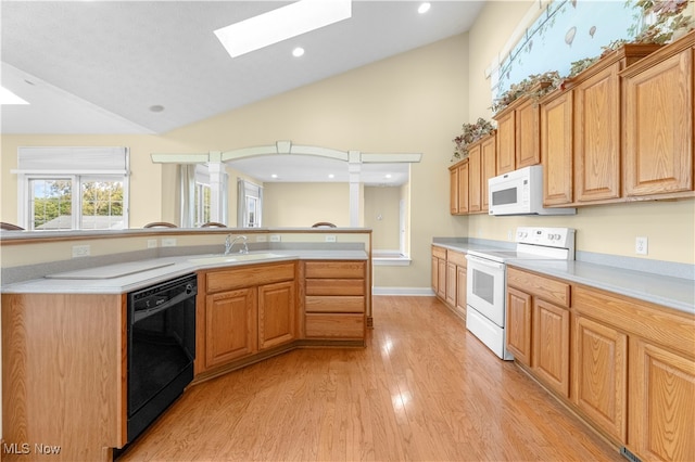 kitchen with vaulted ceiling with skylight, light wood-type flooring, sink, and white appliances