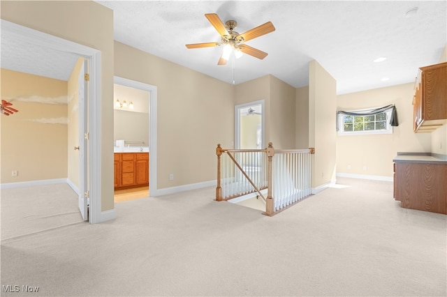 interior space with connected bathroom, ceiling fan, and light colored carpet