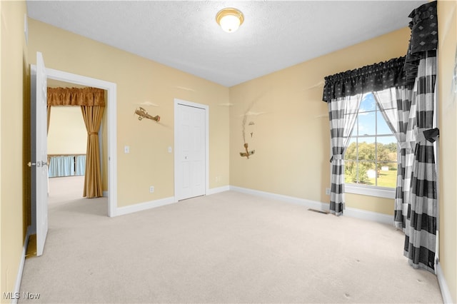 unfurnished room with a textured ceiling and light colored carpet