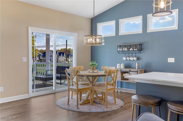 dining area featuring a notable chandelier, wood-type flooring, and vaulted ceiling