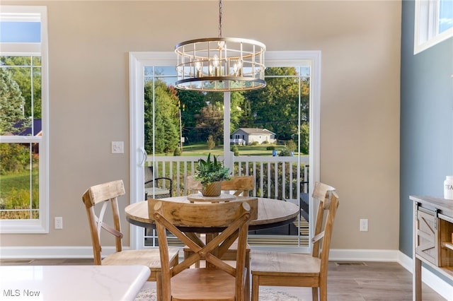 dining room with light wood-type flooring, a chandelier, and a wealth of natural light