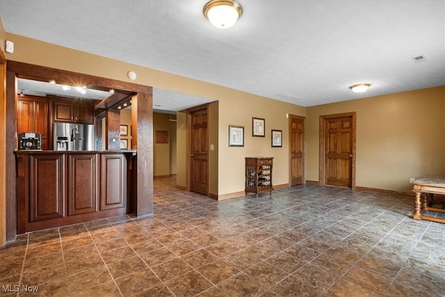 interior space with stainless steel fridge with ice dispenser, a textured ceiling, and dark tile patterned floors