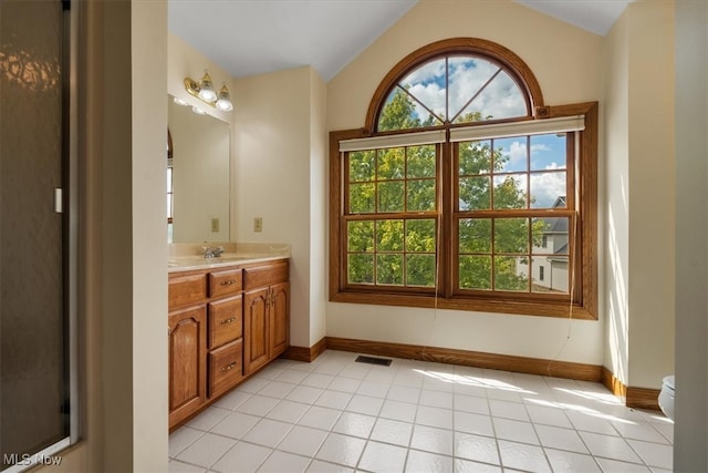 bathroom featuring vanity, vaulted ceiling, tile patterned floors, and a healthy amount of sunlight