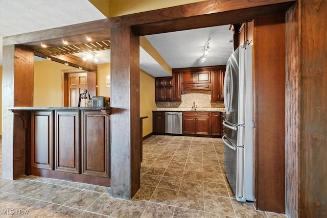 kitchen with stainless steel appliances, sink, kitchen peninsula, rail lighting, and backsplash