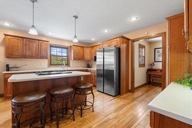 kitchen featuring pendant lighting, light wood-type flooring, a center island, and stainless steel fridge