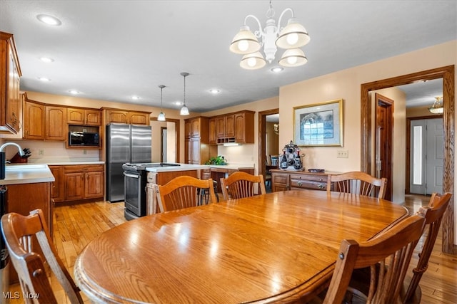 dining area with sink, a notable chandelier, and light hardwood / wood-style flooring