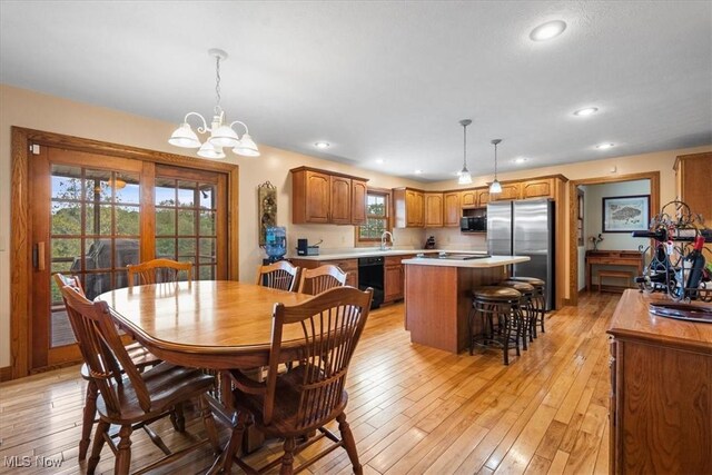 dining area featuring light hardwood / wood-style floors, sink, and a notable chandelier