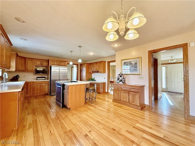 kitchen featuring appliances with stainless steel finishes, a breakfast bar area, decorative light fixtures, a center island, and sink