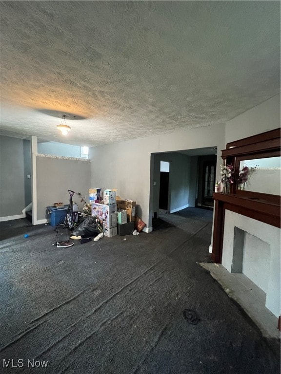 unfurnished living room with dark carpet and a textured ceiling