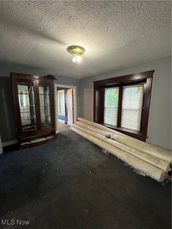 unfurnished living room featuring carpet and a textured ceiling