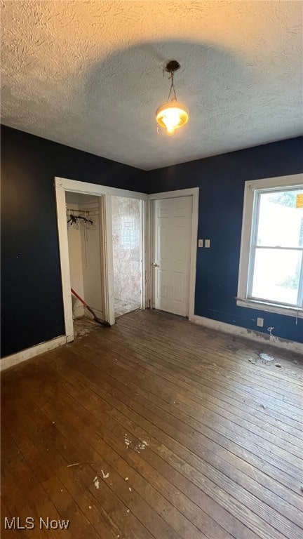 unfurnished bedroom featuring a textured ceiling, hardwood / wood-style floors, and a closet