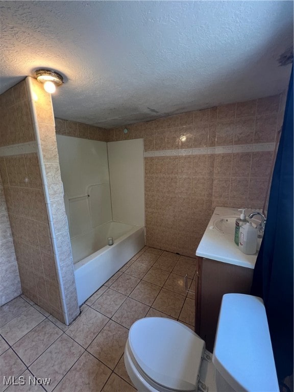 full bathroom featuring tile walls, tile patterned flooring, a textured ceiling, vanity, and toilet