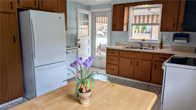 kitchen featuring white appliances, sink, and light tile patterned floors