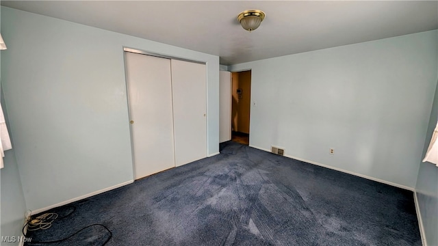 unfurnished bedroom featuring dark carpet and a closet