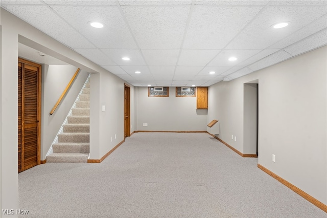 basement with a drop ceiling and light colored carpet