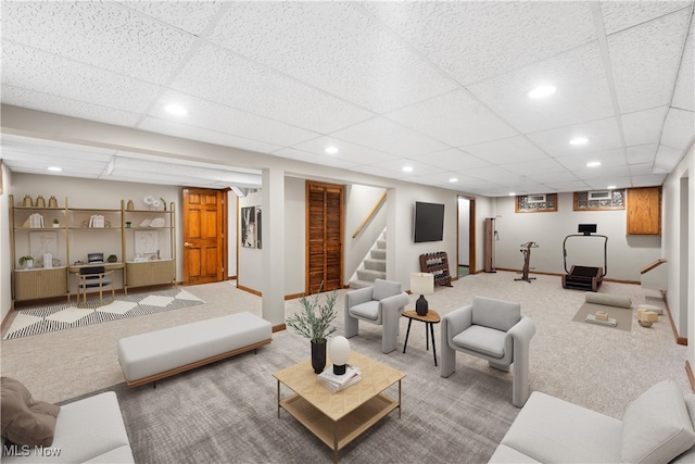 living room featuring carpet floors and a drop ceiling