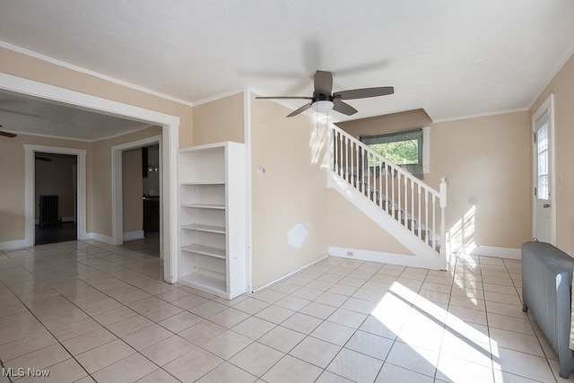 spare room with ceiling fan, crown molding, and light tile patterned floors