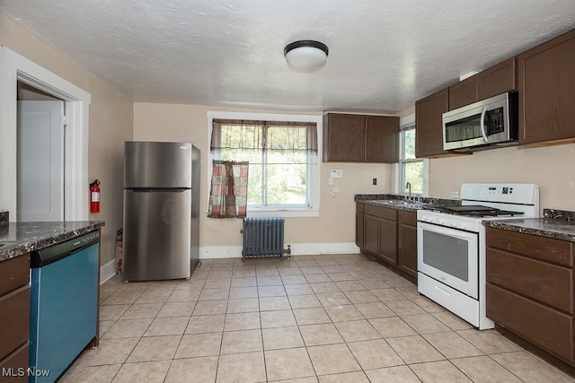 kitchen featuring dark brown cabinets, sink, stainless steel appliances, radiator, and light tile patterned floors