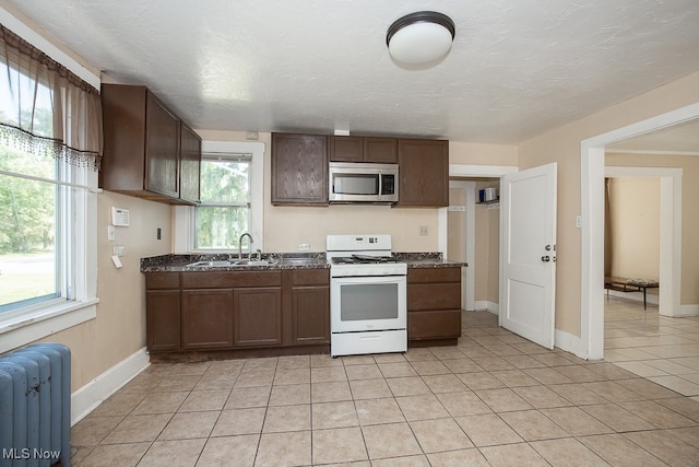 kitchen with plenty of natural light, sink, radiator heating unit, and white gas range oven