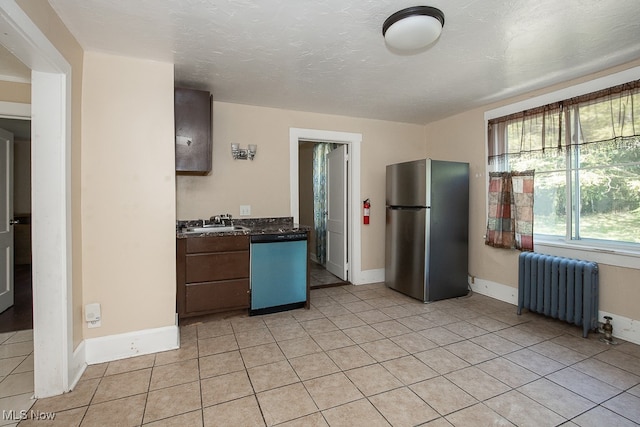 kitchen featuring dark brown cabinets, stainless steel appliances, radiator, and light tile patterned floors