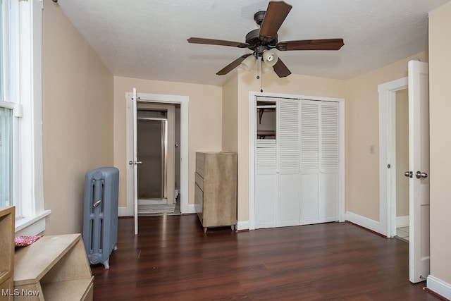 unfurnished bedroom featuring radiator, ceiling fan, a textured ceiling, and dark hardwood / wood-style flooring