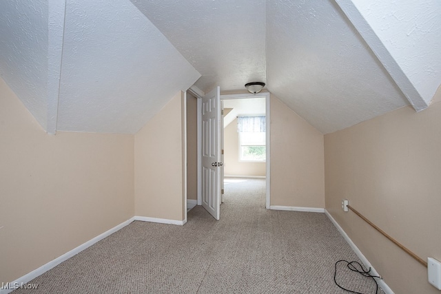 additional living space with light carpet, a textured ceiling, and lofted ceiling