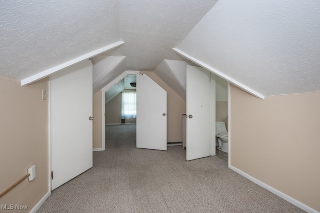 bonus room with a textured ceiling, vaulted ceiling, and light carpet