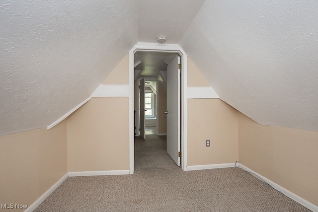 additional living space featuring vaulted ceiling, a textured ceiling, and carpet floors