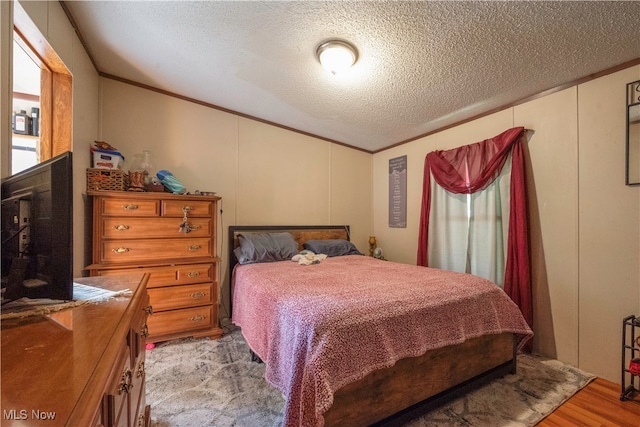 bedroom featuring a textured ceiling, crown molding, and light hardwood / wood-style floors