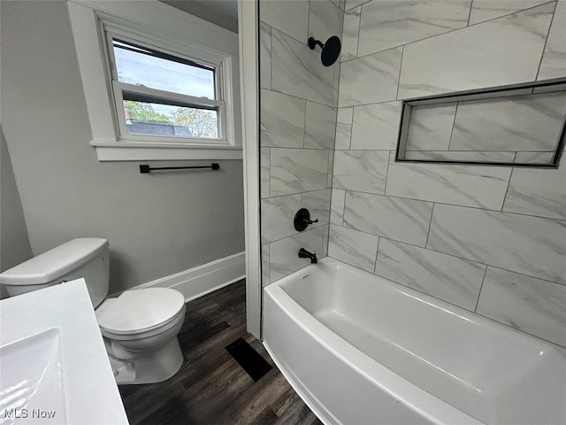 bathroom featuring wood-type flooring, tiled shower / bath combo, and toilet