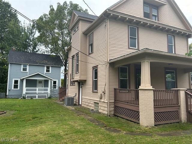 back of house featuring cooling unit, a lawn, and covered porch