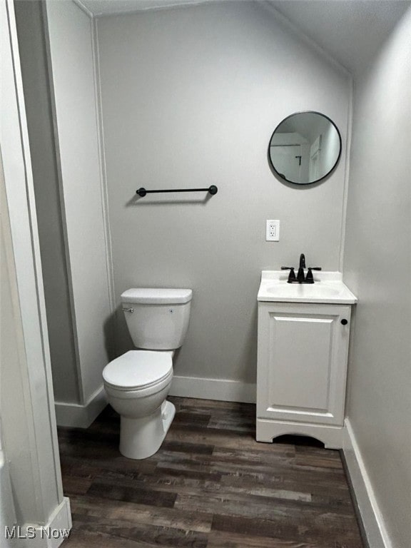 bathroom featuring lofted ceiling, hardwood / wood-style flooring, vanity, and toilet