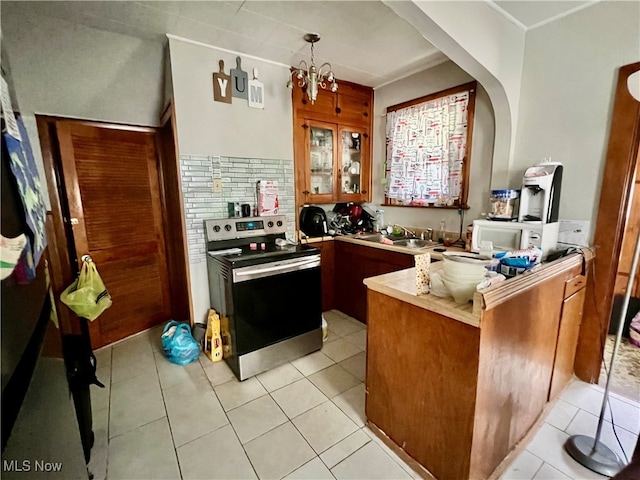 kitchen featuring kitchen peninsula, tasteful backsplash, stainless steel electric stove, an inviting chandelier, and light tile patterned flooring