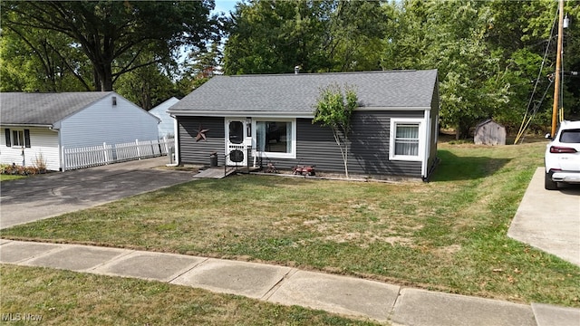 view of front of property with a storage unit and a front yard