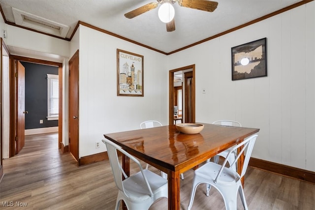 dining area with ceiling fan, hardwood / wood-style flooring, wood walls, and ornamental molding