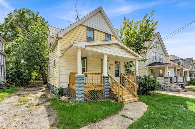 bungalow-style house featuring covered porch and a front yard