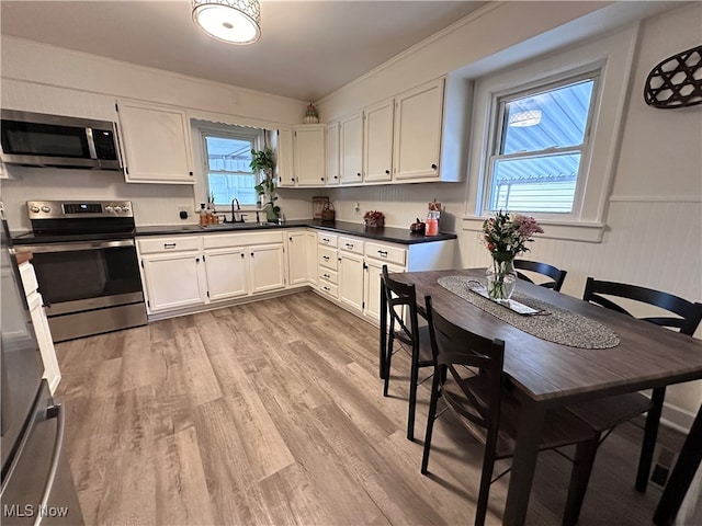 kitchen featuring stainless steel appliances, white cabinets, light wood-type flooring, and sink